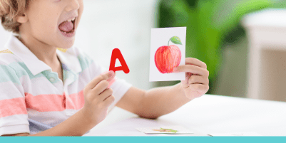 a small child holds up a red letter A and a picture of a red apple